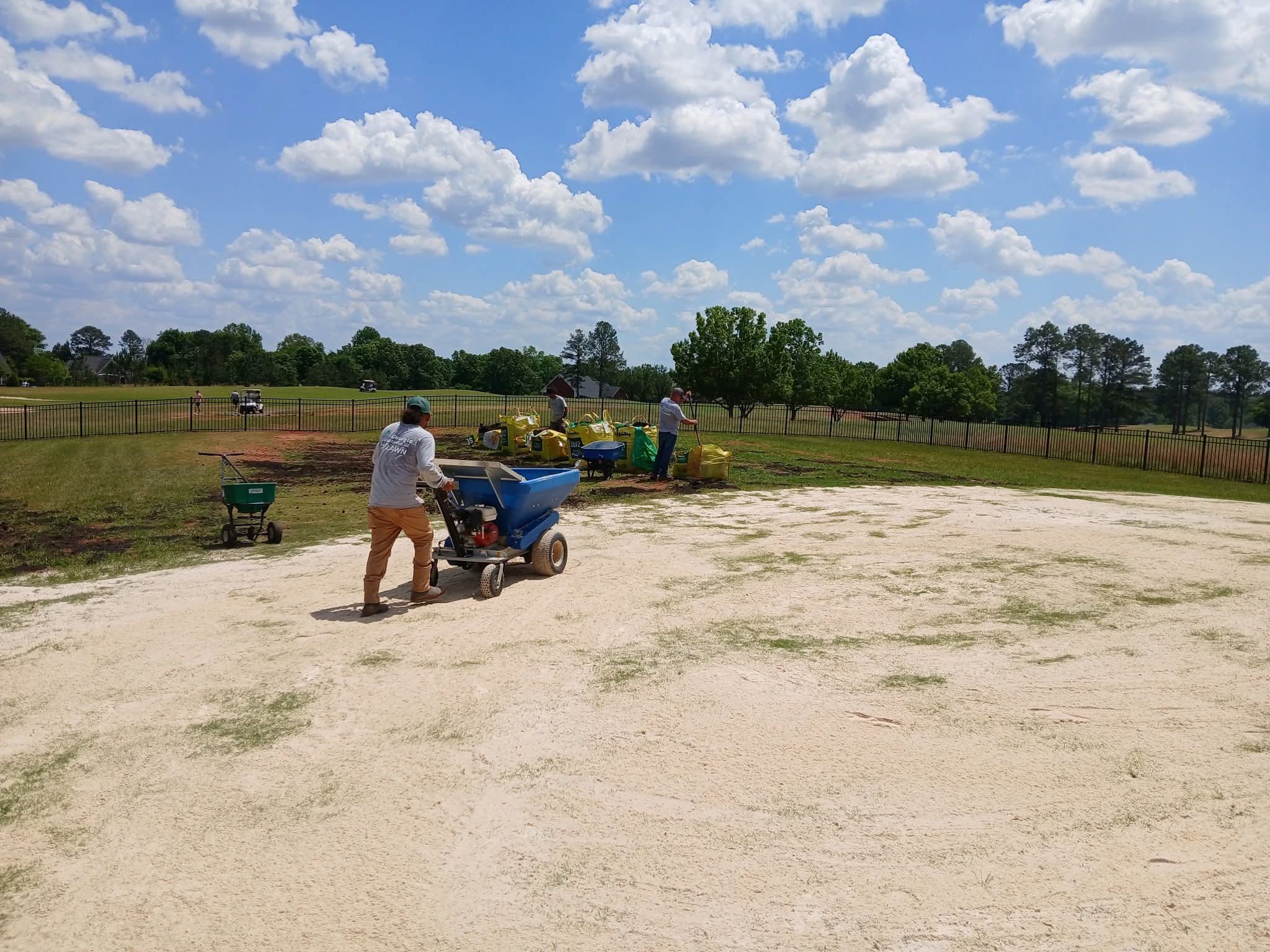 GLC crew at work top dressing a lawn beside a golf course