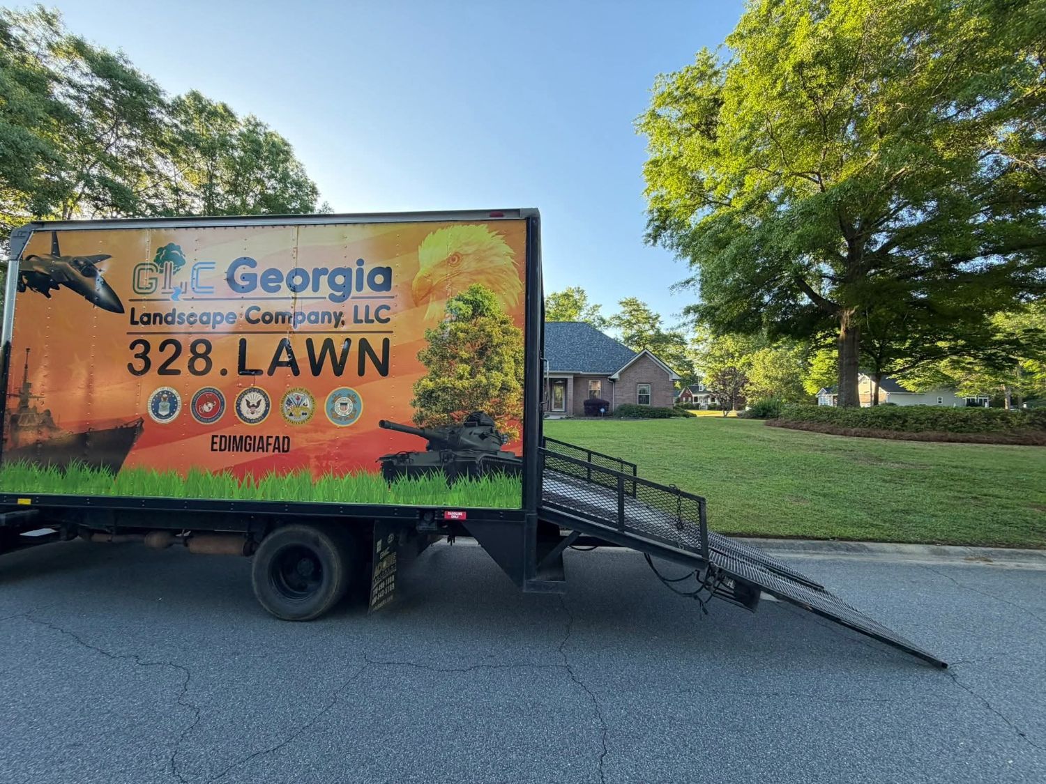 GLC box truck with its ramp down at a job beside a green lawn